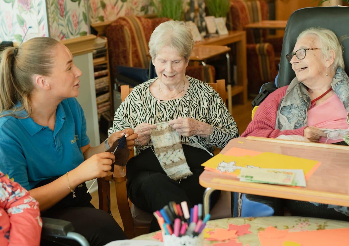 A support worker enjoying a craft activity with two older women