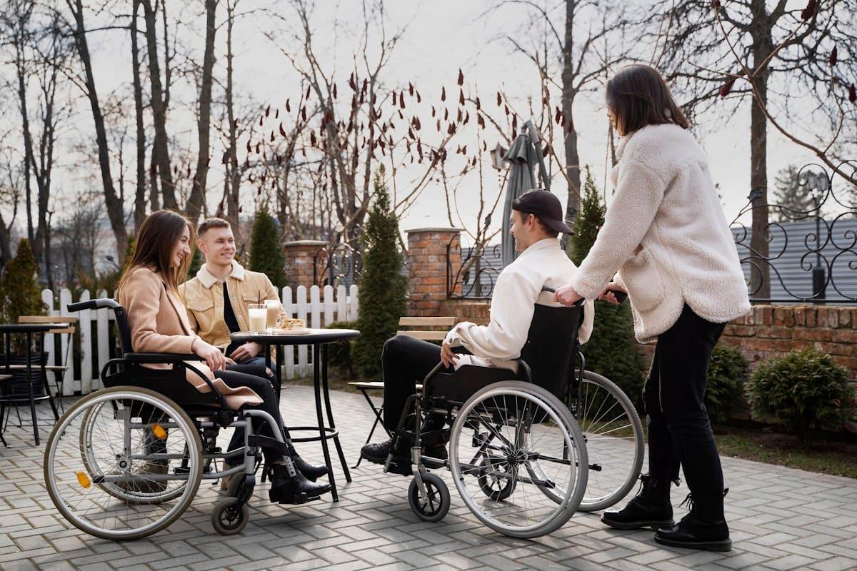 A group of friends, two using wheelchairs, socialising at an outdoor cafe