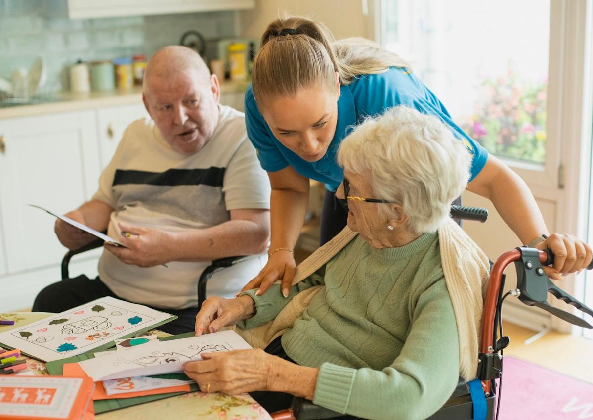 A carer doing an activity at the table with an elderly couple