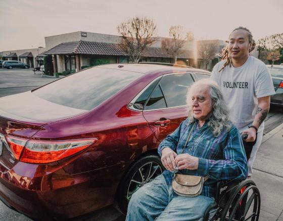 A support worker pushing an older man in a wheelchair outdoors