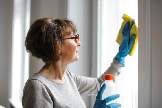 A support worker cleaning a bench in a bright kitchen